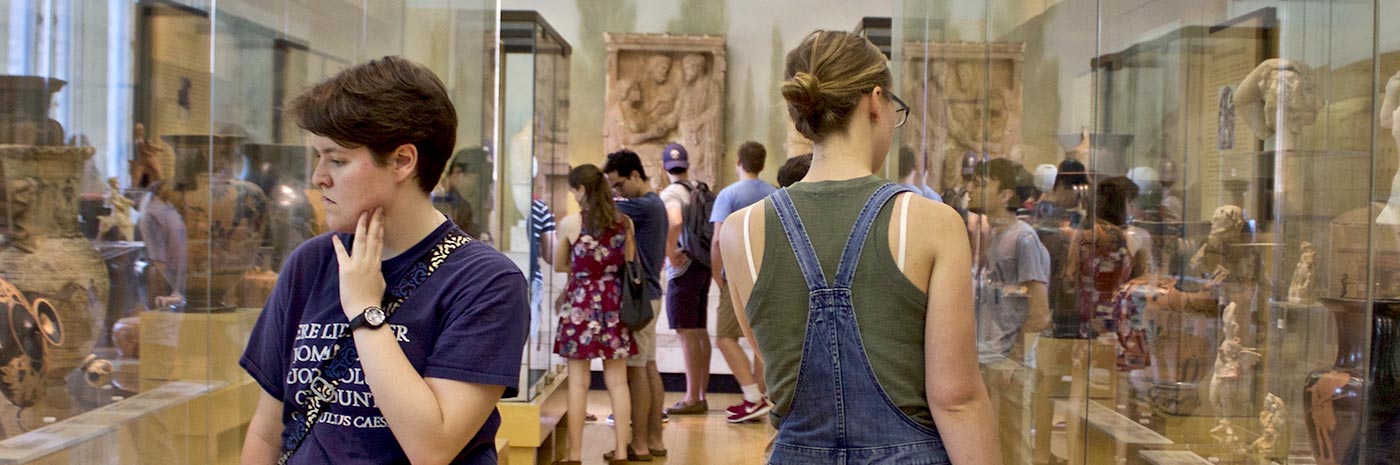 Two students examining glass cases filled with sculptures