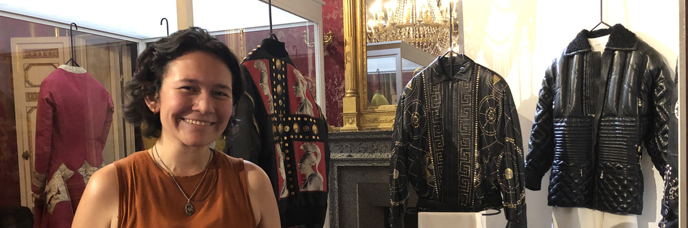 a student with various wardrobe items on display in glass cases behind them