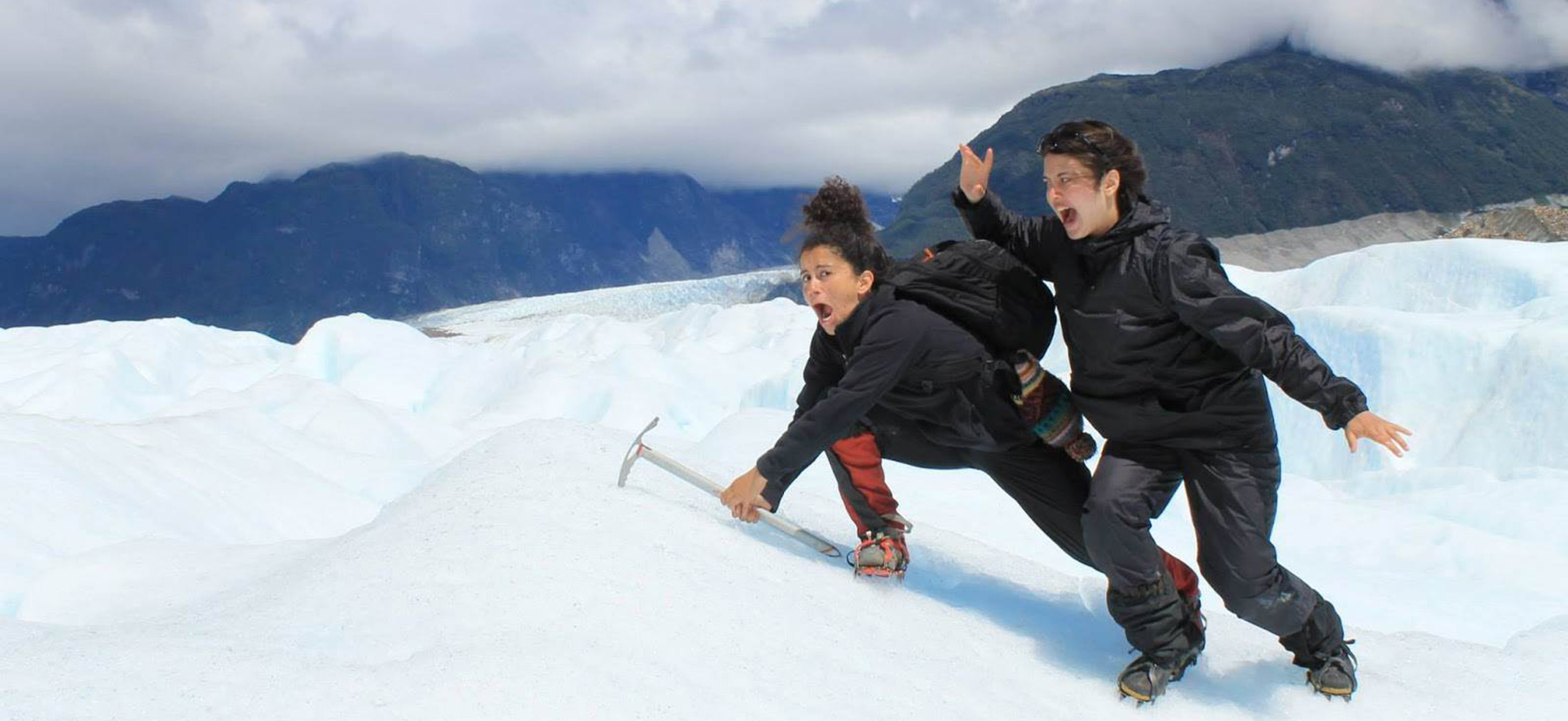 Two students climbing a snow-covered mountain and mugging for the camera