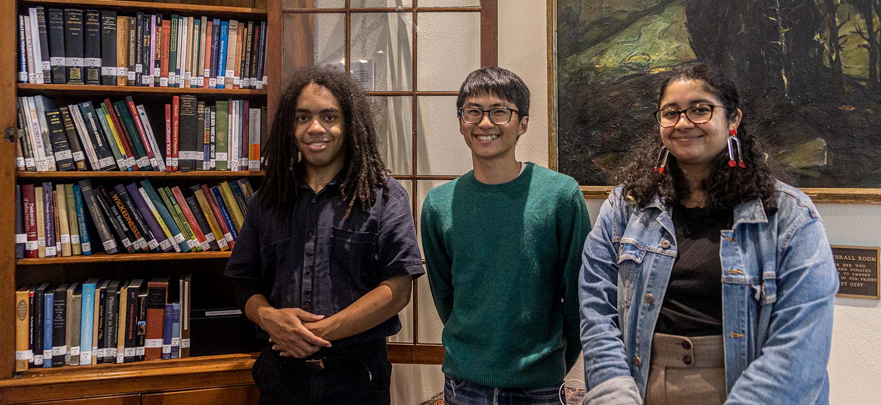 Three students pose with a new collection of diverse philosophy texts named in their honor