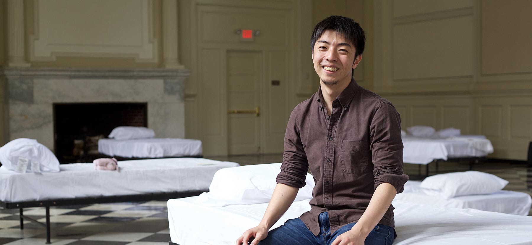 Yoshifumi Nomura sitting on a bed in Founders Hall