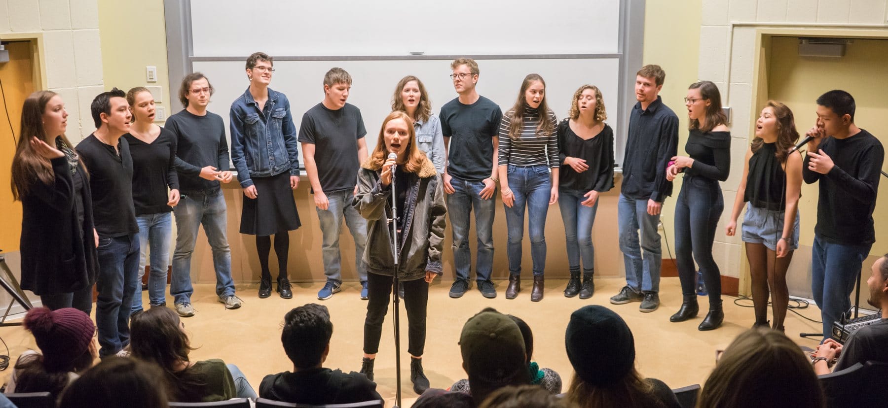 An acapella group performs with a woman singing solo in front. 