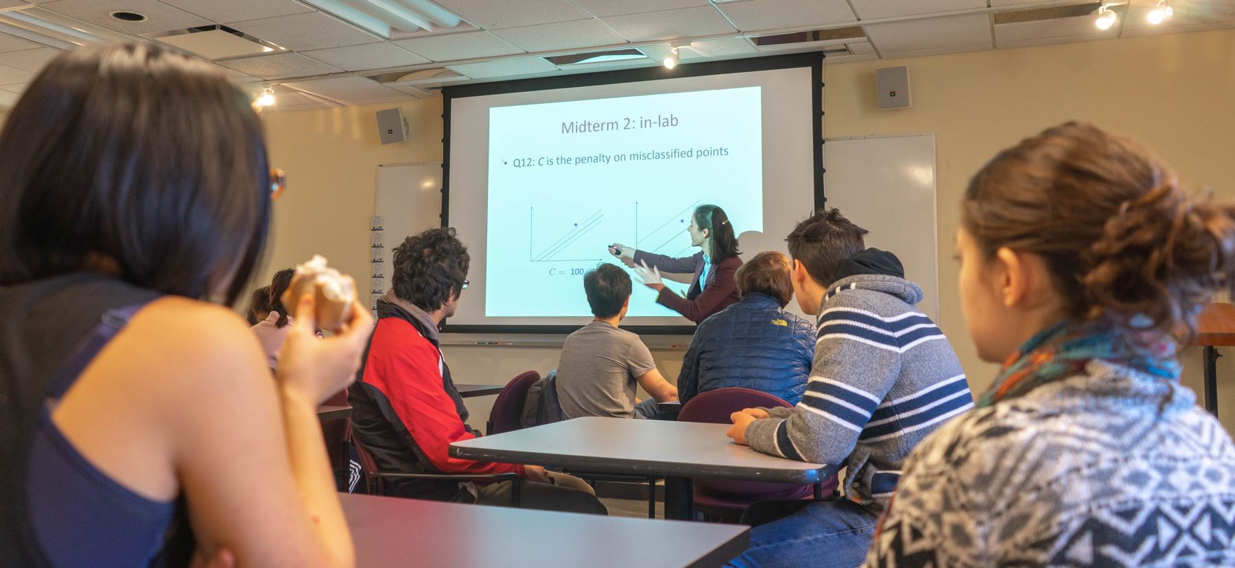 A woman presents in a classroom to a group of students
