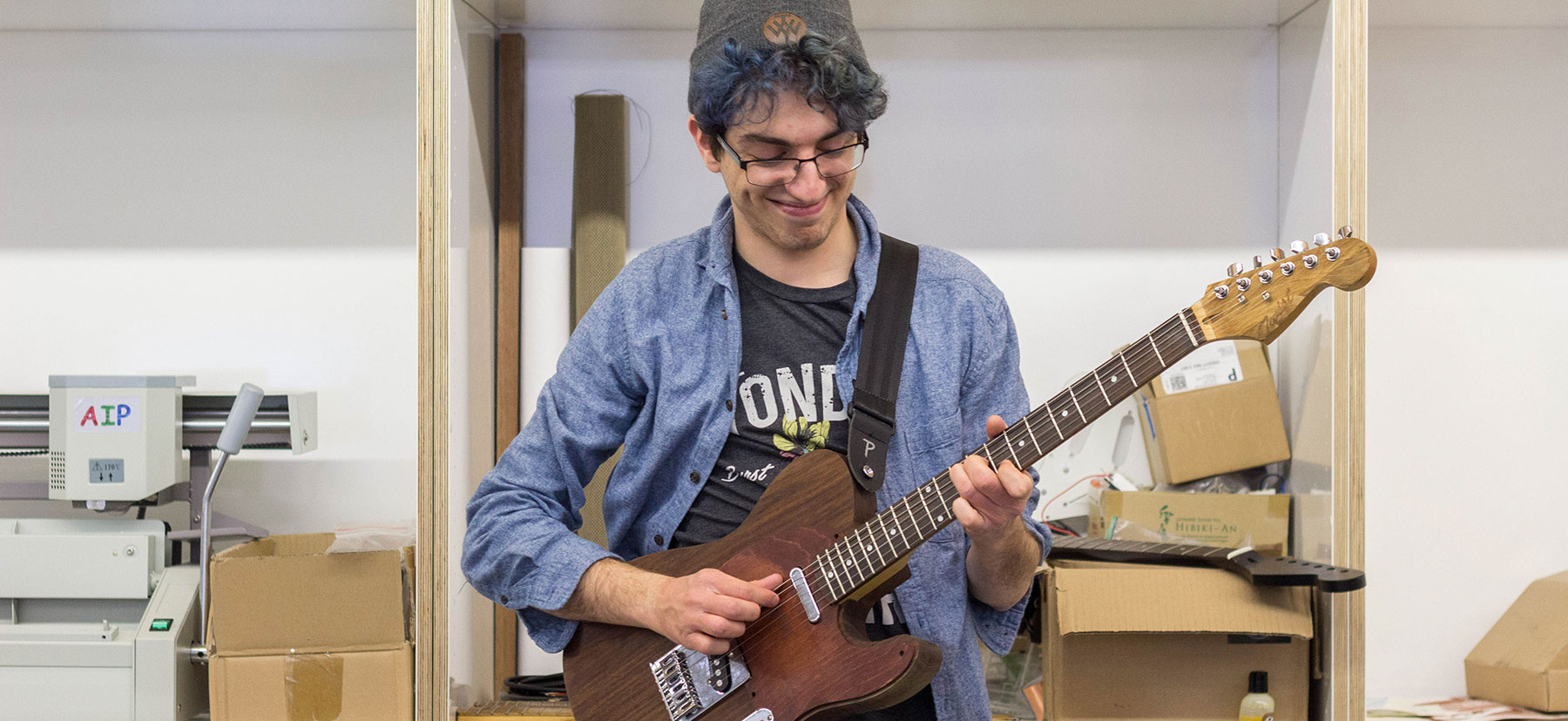 Micah Maben poses with a guitar created in VCAM's Maker Space