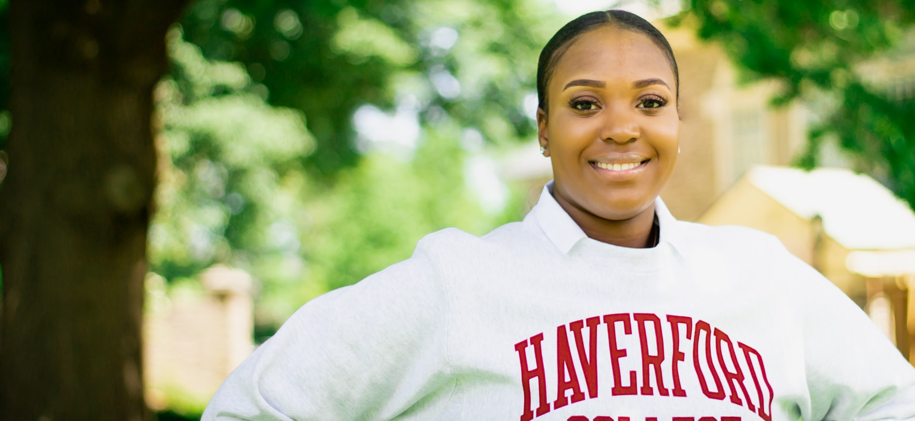 a woman stands in front of trees wearing a Haverford College sweatshirt.