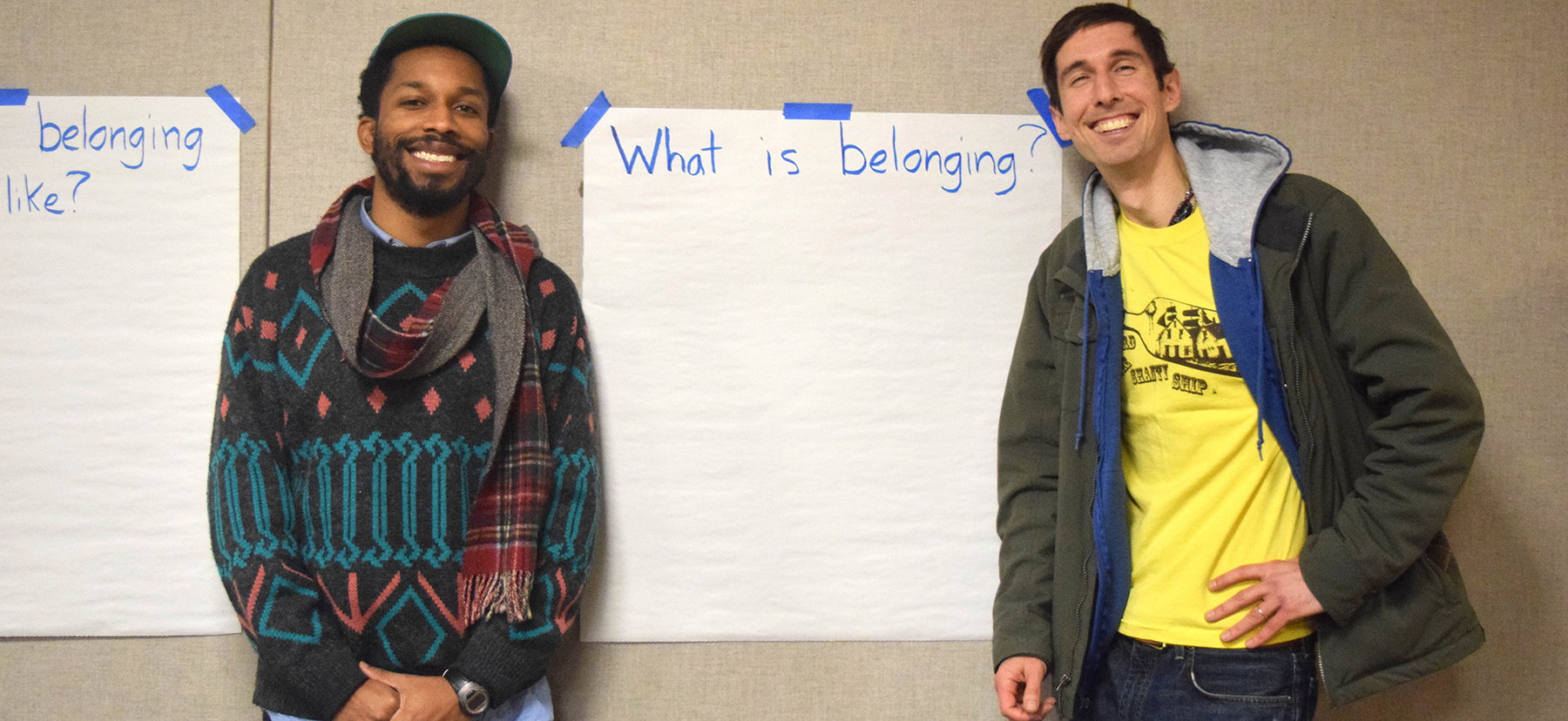 Sterling Duns and Caselli Jordan stand in front of a large piece of paper asking what "belonging" is