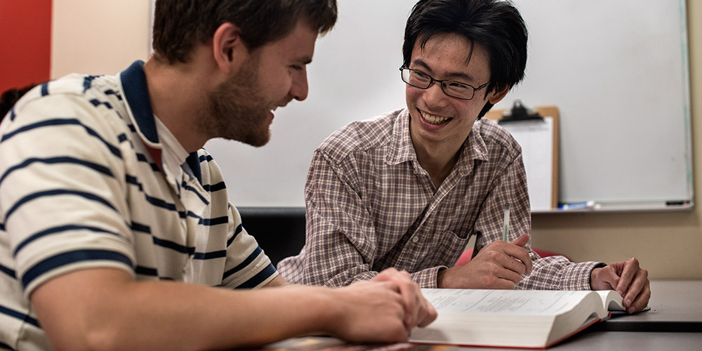 Two students smiling together during a tutoring session