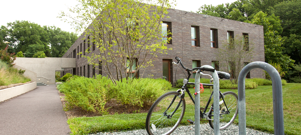 A bicycle leans against a bike rack in front of Kim Hall