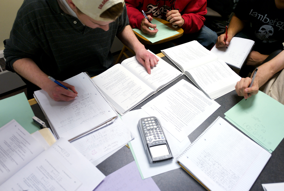 papers and a calculator scattered across a table where students work