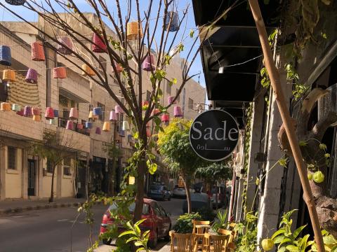 Street scene of cafe with a sign reading Sade in English followed by Arabic
