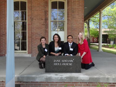 Four students kneel in front of the Abigail Hull House sign in Chicago