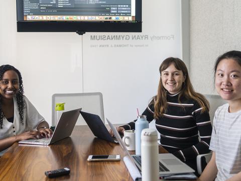 The three women who make up the Gradual incubator team work at laptops on their project