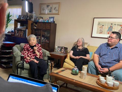Professor Reid photographed from behind as he interviews Kiyo Fujiu, her daughter, and grandson in their home