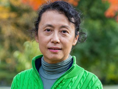 Weiwen Miao is photographed outside wearing a turtleneck and a bright green sweater