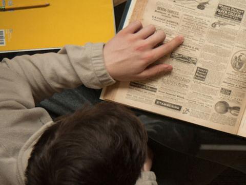 a student examines and old newspaper