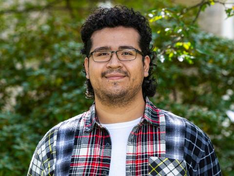 Photo of Henry Morales in a flannel shirt in front of some Haverford greenery