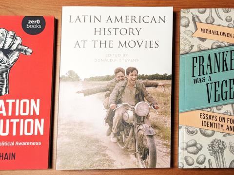 Three book covers: Education Revolution, a raised fist holding a pencil on red background; Latin American History at the Movies, two men laughing and riding a motorcycle; Frankenstein was a Vegetarian, drawings of food and one image of Frankenstein's face