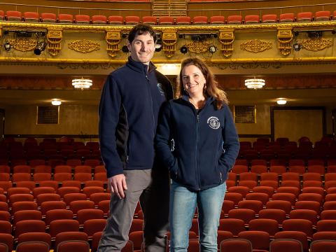 Pictured is Bryan Halperin '95 and Johanna Bloss Halperin BMC '94, standing on stage in the Colonial Theater in Laconia, N.H.