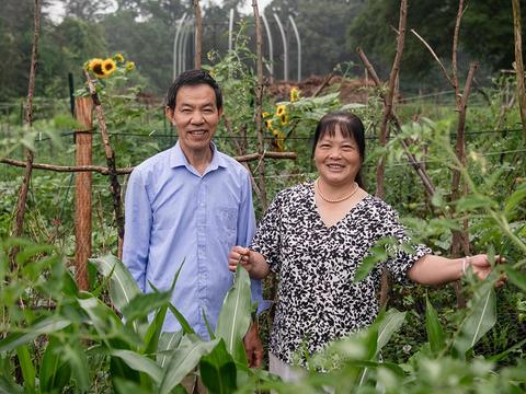 Professor Foen Peng's parents stand in the center of a lush community garden at the Haverfarm.
