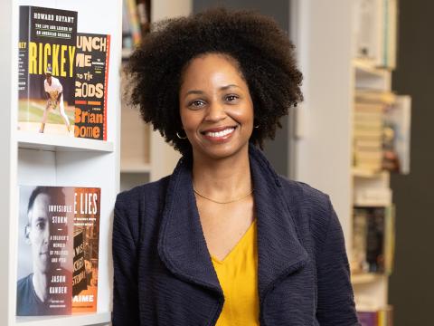 Rakia Clark '01 stands in front of a bookshelf, smiling.