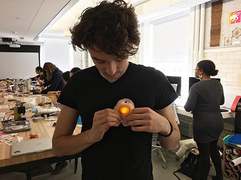 Student holds glowing object over heart while staring down at his creation