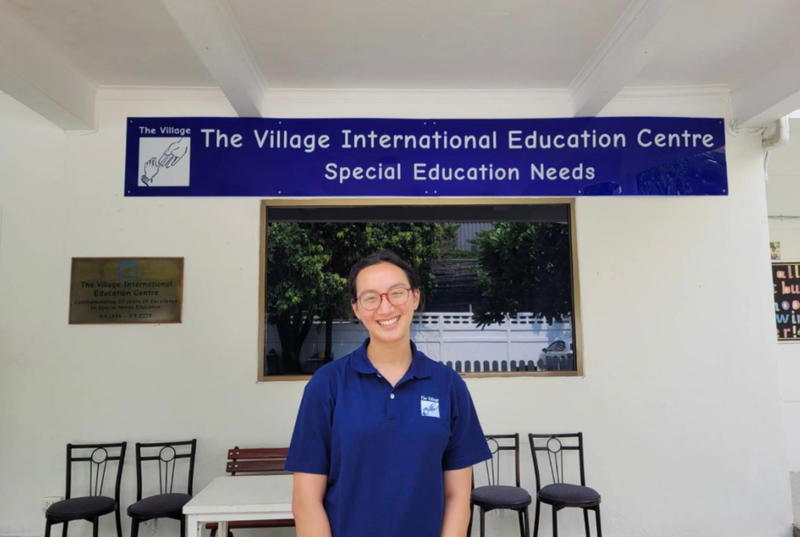 Elena standing in front of the Bangkok at the Village Education Center sign