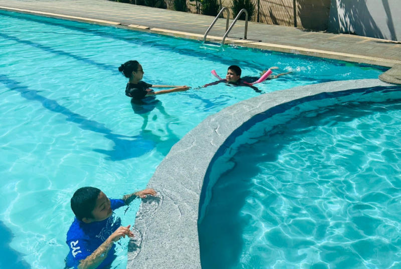 Elena and two children swim in a pool.