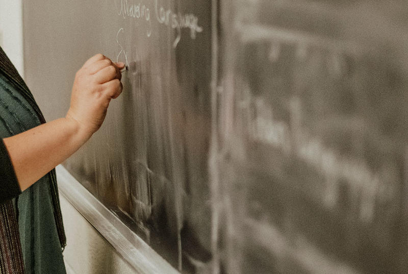 Faculty member writes on a blackboard