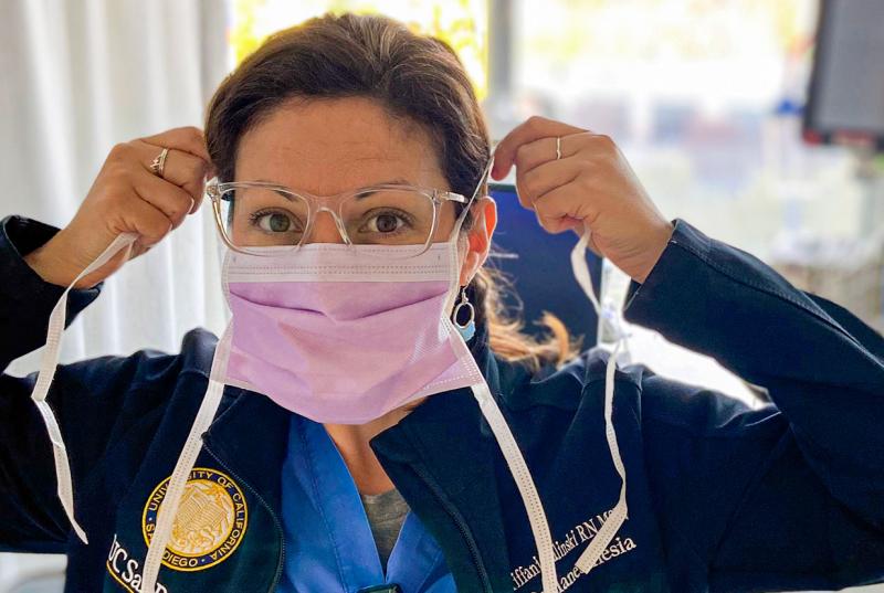 Nurse Tiffani Zalinski wears scrubs and puts on her surgical mask