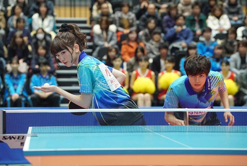 A couple with fierce expressions poised to play table tennis