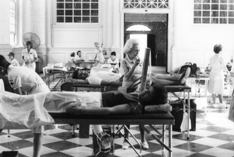 black and white photo of the Great Hall being used for a blood drive, with donors lying in beds and nurses working