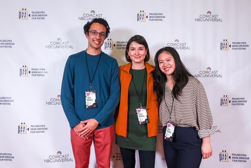 Assistant Professor Emily Hong stands in front of a white screen flanked by two students