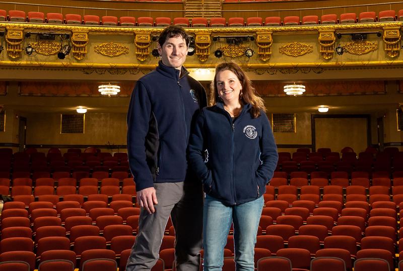 Pictured is Bryan Halperin '95 and Johanna Bloss Halperin BMC '94, standing on stage in the Colonial Theater in Laconia, N.H.