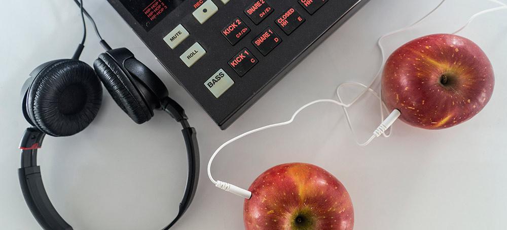 Two apples hooked up to wires feeding into headphones and other equipment