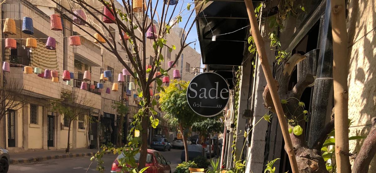 Street scene of cafe with a sign reading Sade in English followed by Arabic