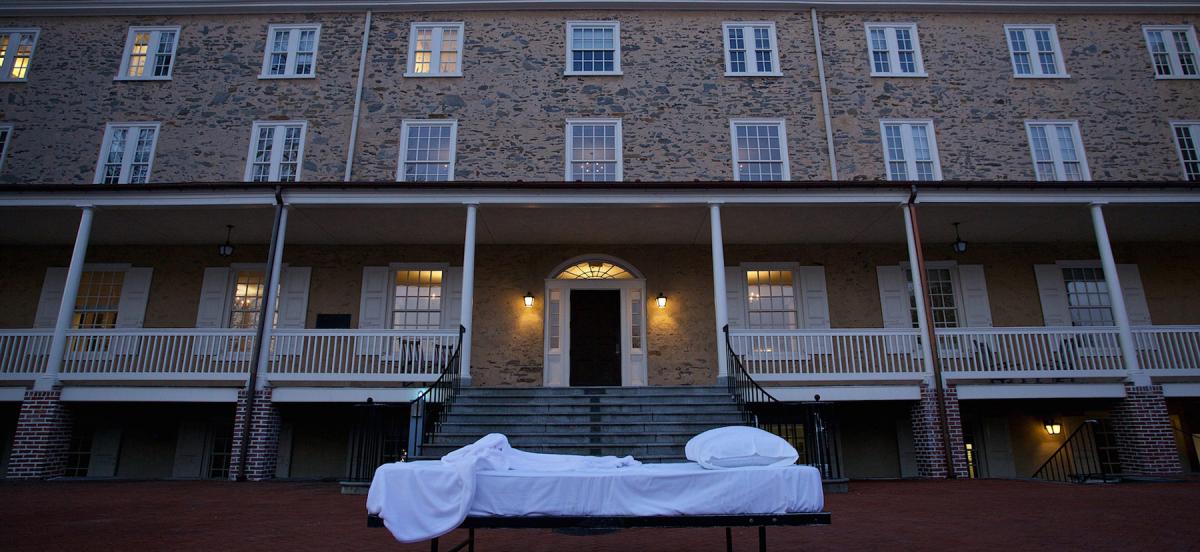 A student's bed in front of Founders Hall