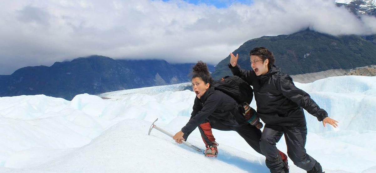 Two students climbing a snow-covered mountain and mugging for the camera
