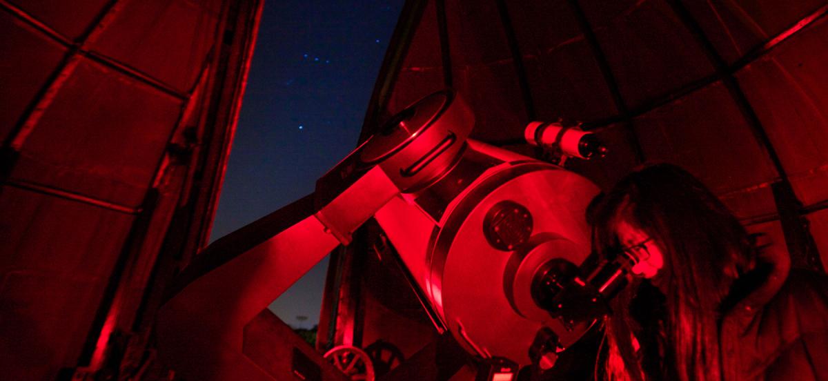 A student observing the night sky through a telescope
