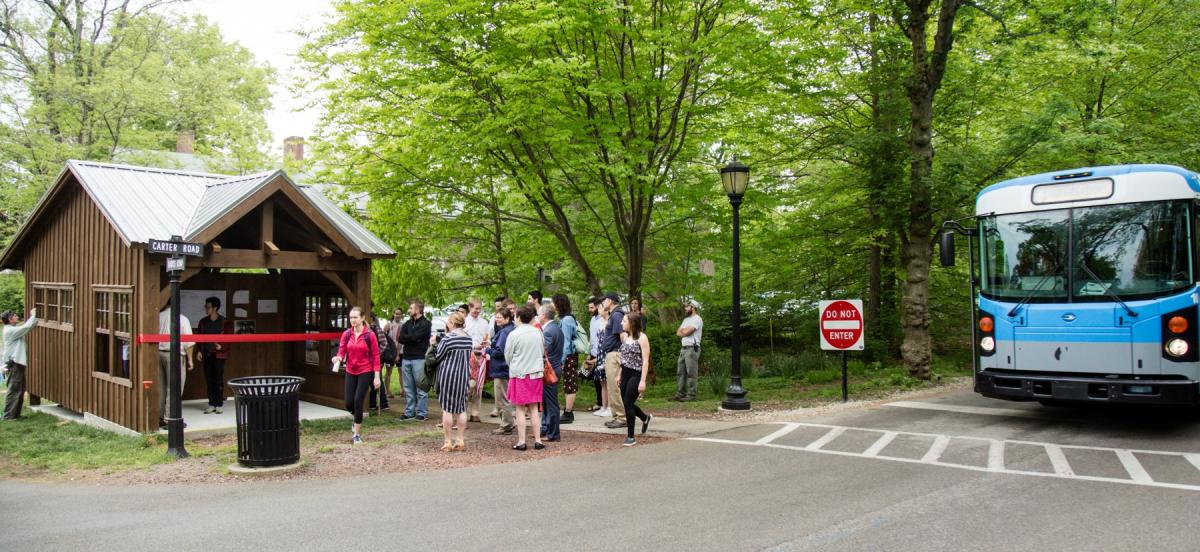 A bus stop on campus with a crowd of people and a bus
