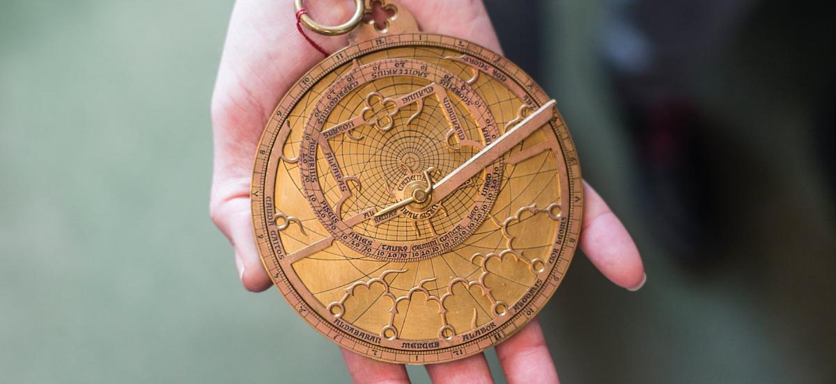 A hand holding an astrolabe.