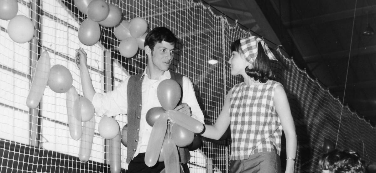 A man and a woman hang balloons in the Field House circa 1965