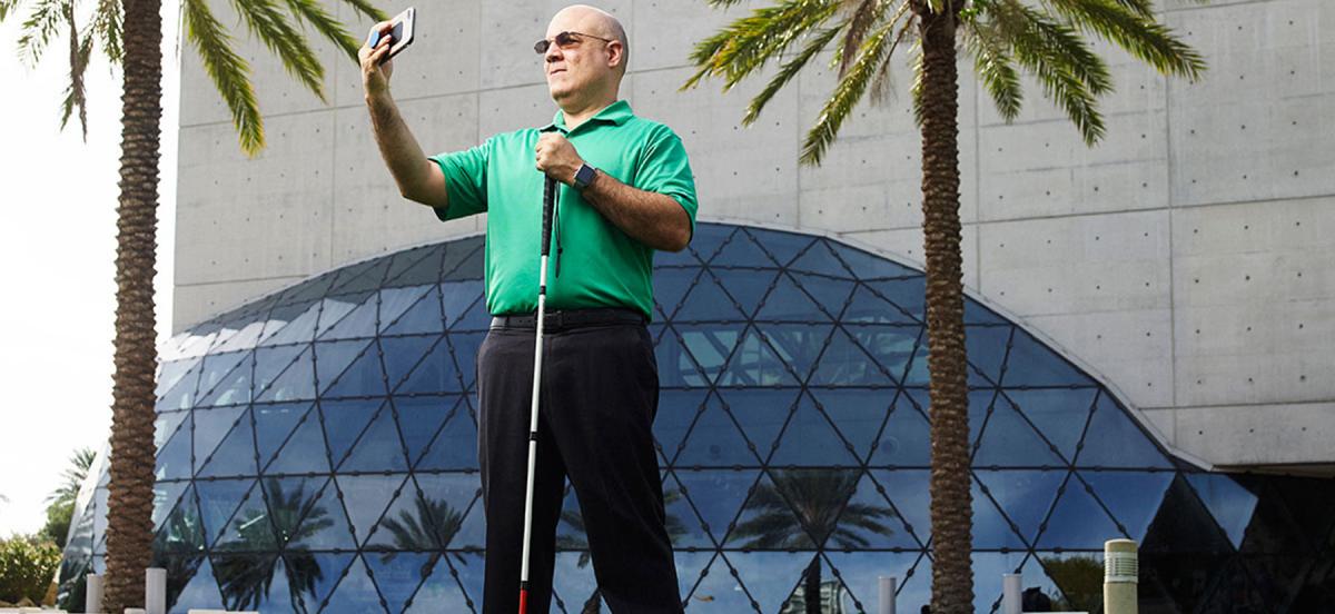 Bob Croslin using a cane and a camera phone