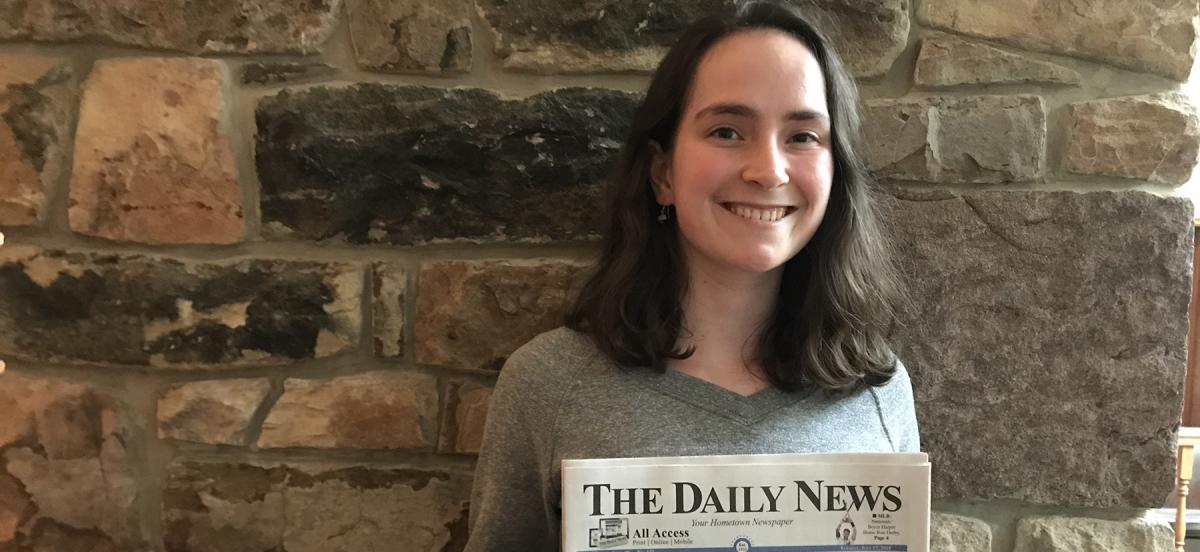 Molly Biddle holding the newspaper where she is interning