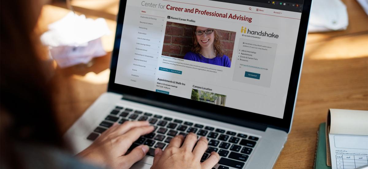 A laptop screen, viewed over the shoulder of an unseen student, showing the homepage for the Center for Career and Professional Advising