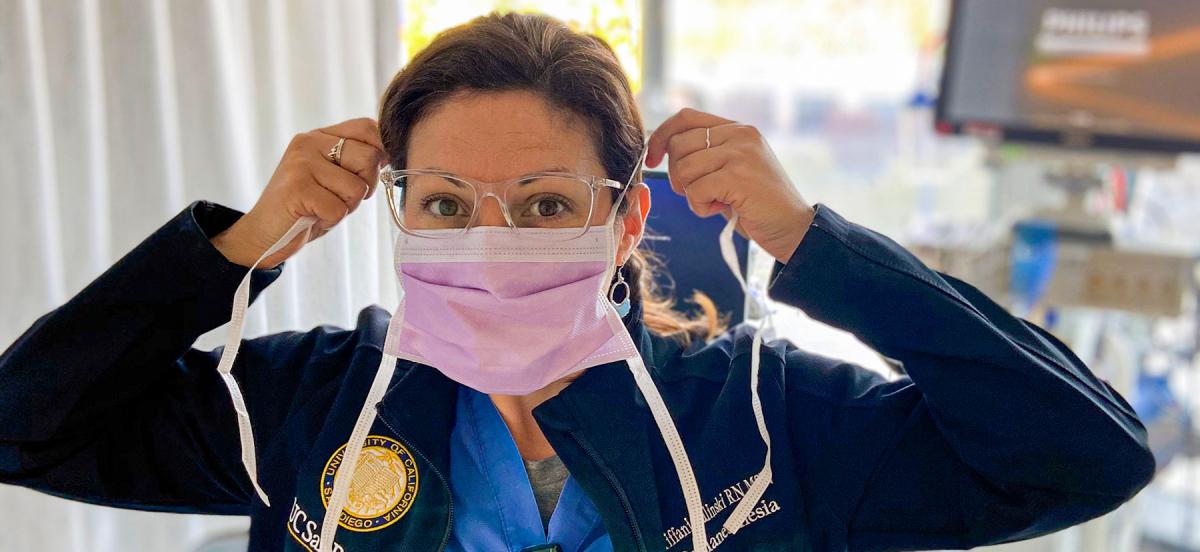 Nurse Tiffani Zalinski wears scrubs and puts on her surgical mask