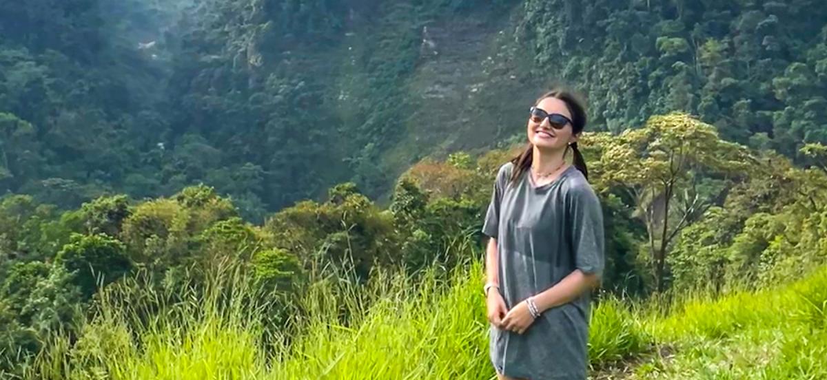 Chase wears sunglasses surrounded by lush green fields and mountains on a hike in Colombia