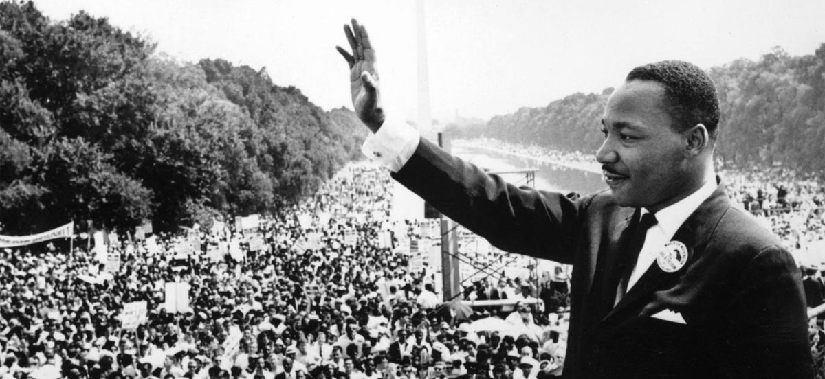 Martin Luther King, Jr. with his hand raised speaking to the crowd on the Mall during the March on Washington.
