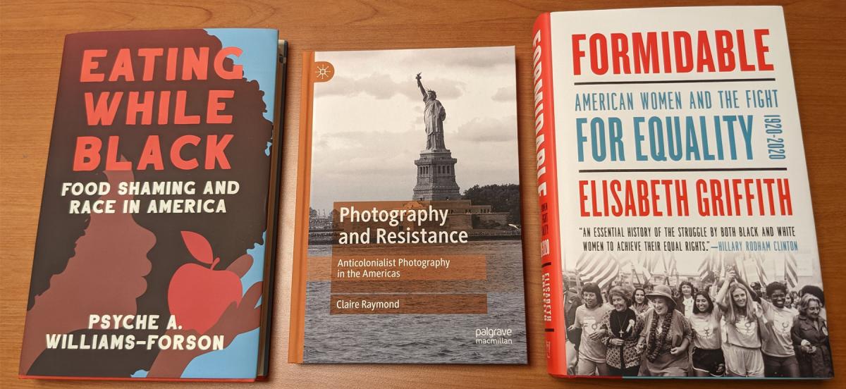Photo of three books. Eating While Black features a silhouette of a Black woman holding an apple. Photography and Resistance features a sepia photo of the Statue of Liberty. Formidable features a black and white photo of women at a protest.