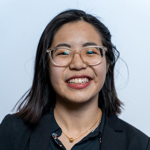 Headshot of Rebecca Chang, smiling for the camera against a sky blue backdrop