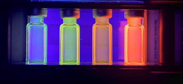 Four vials containing quantum dots are shown absorbing UV light and re-emitting light at a different wavelength, which creates the vibrant glowing colors. Ethan Baker '24, First Place Winner, 2022 KINSC Scientific Imaging Contest.